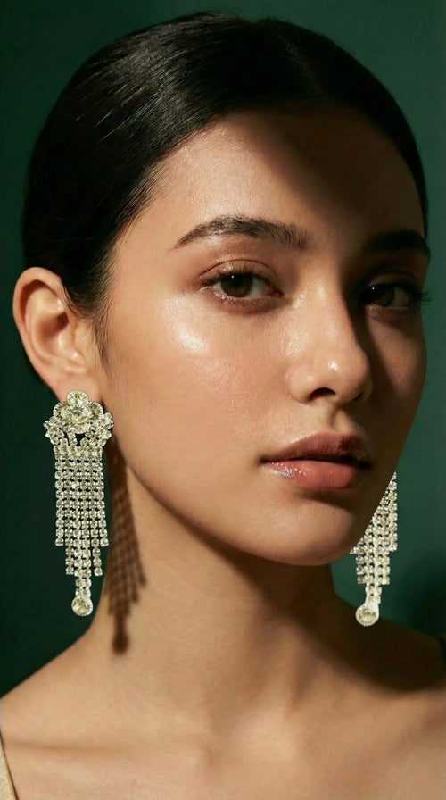 Long chandelier earrings with multiple cascading rows of clear sparkling gemstones, worn by a model with sleek dark hair.