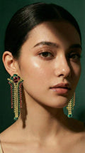 Gold chandelier earrings featuring red and green gemstones with multiple rows of small sparkling stones hanging in a teardrop shape.