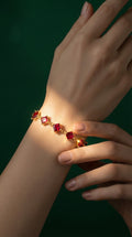 Gold bracelet featuring square red gemstones linked together, worn on a wrist.