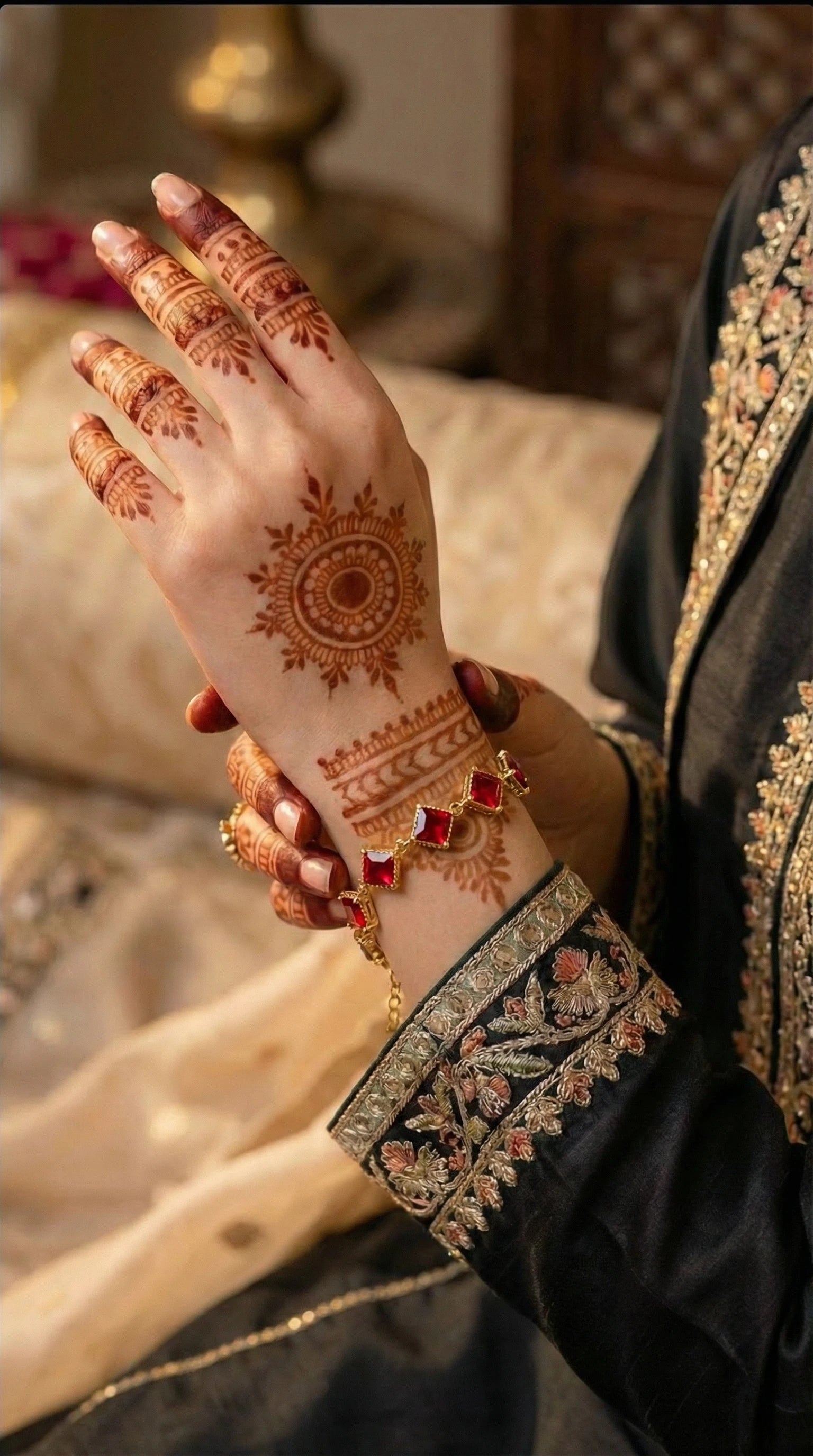Gold bracelet featuring square red gemstones linked together, worn on a wrist.