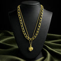 Gold chain necklace with a pendant on a black mannequin bust against a green fabric background