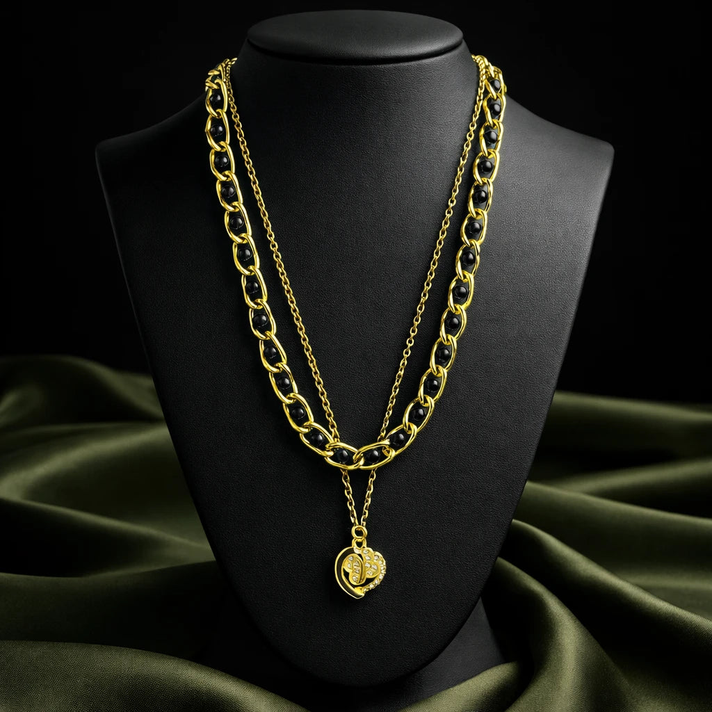 Gold chain necklace with a pendant on a black mannequin bust against a green fabric background