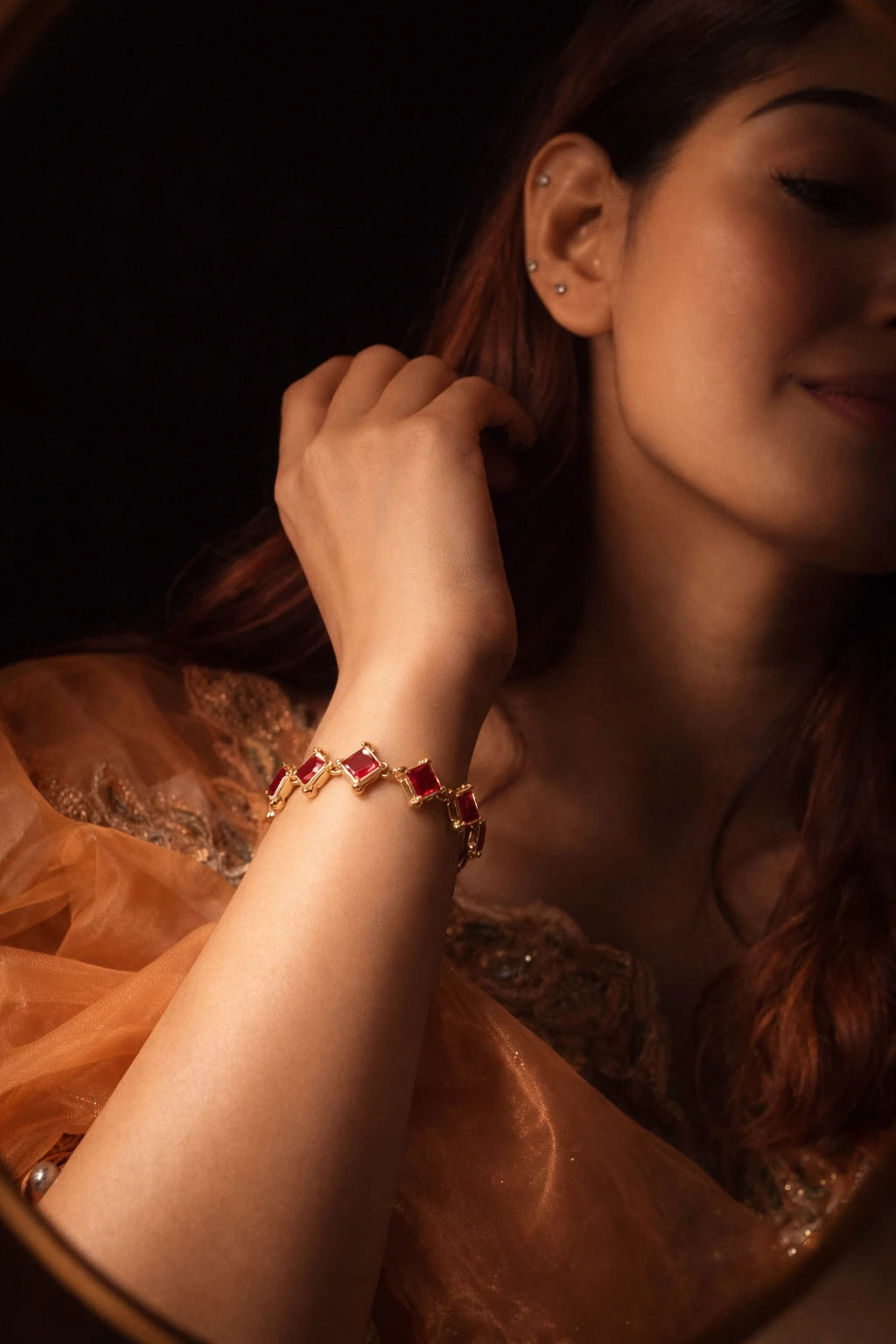 Gold bracelet featuring square red gemstones linked together, worn on a wrist.