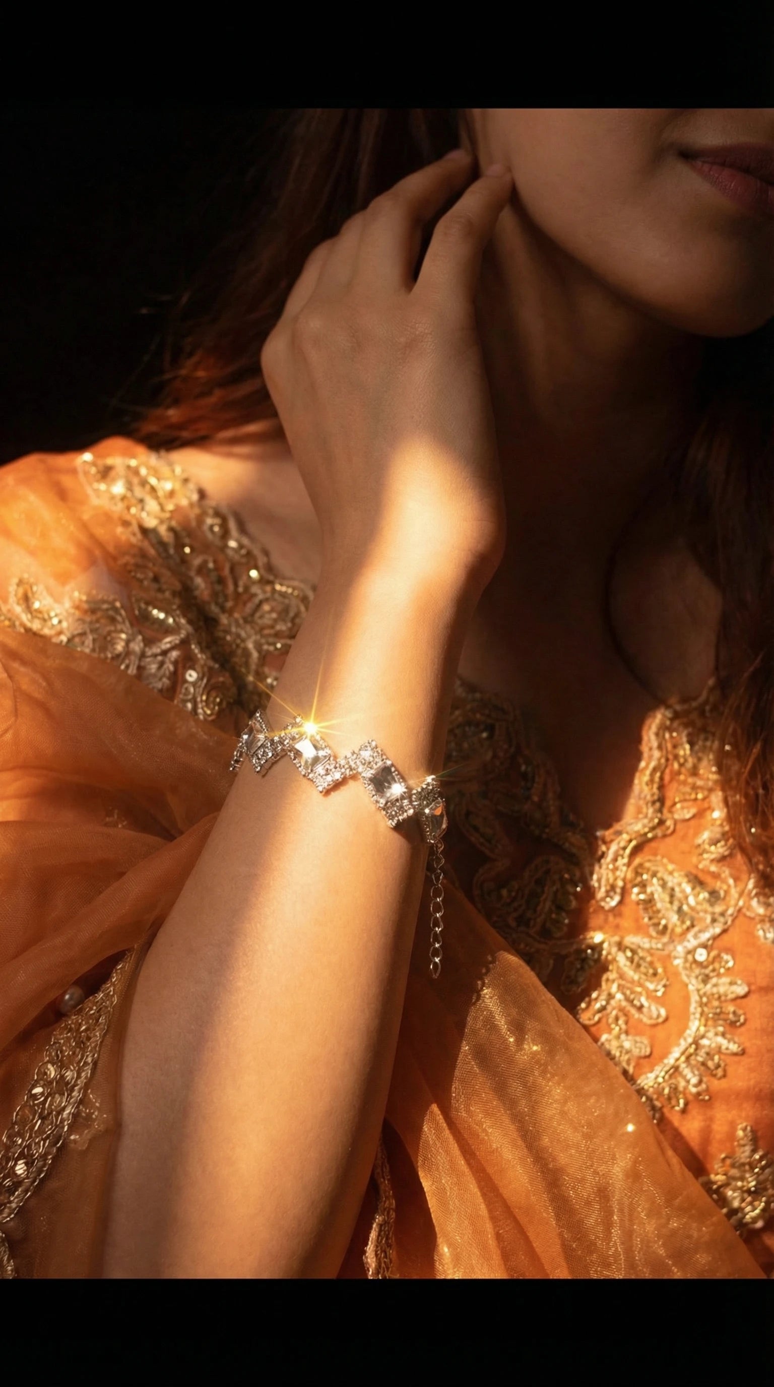 Silver bracelet with alternating square and round clear gemstones arranged in a zigzag pattern, worn on a wrist.