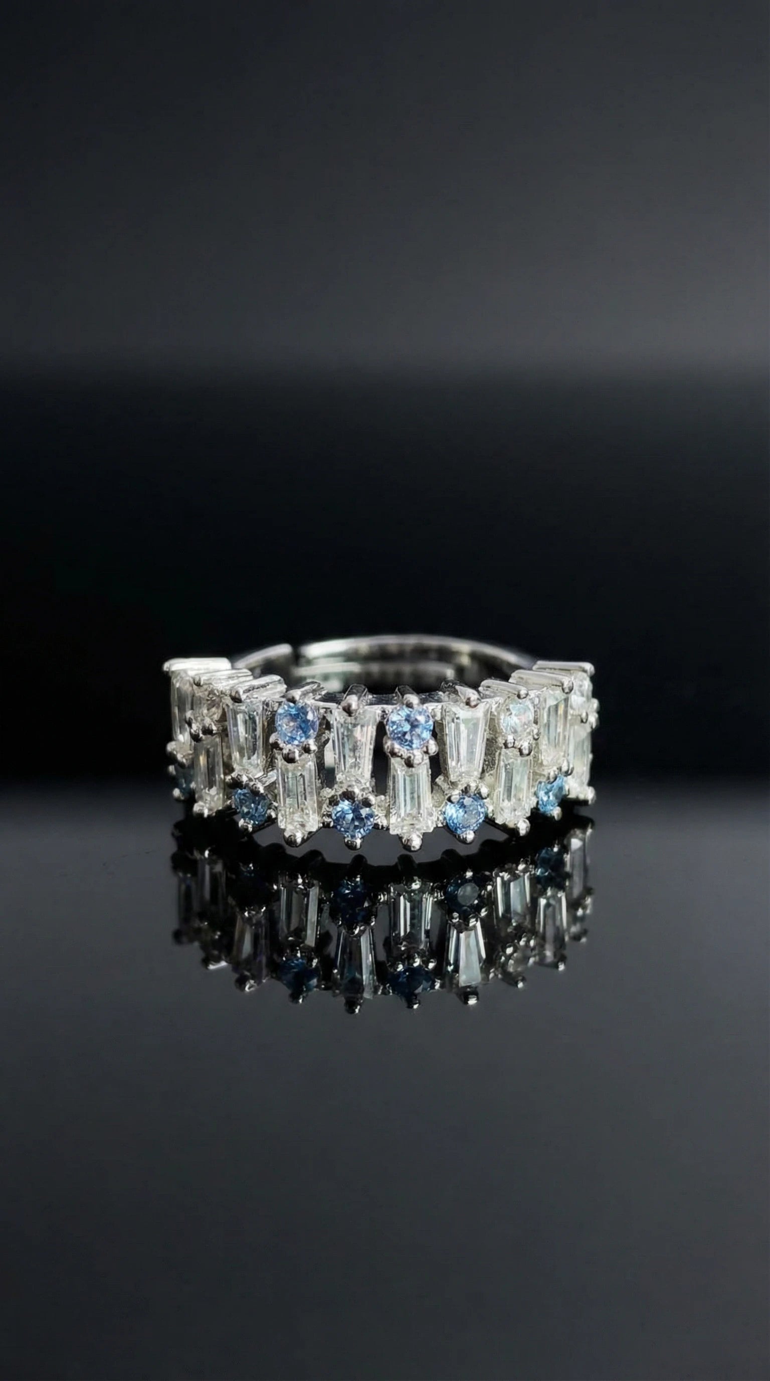Silver ring alternating round blue gemstones and tapered baguette clear stones set in a continuous band