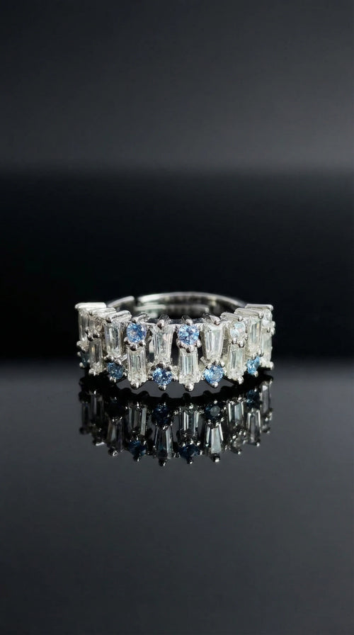 Silver ring alternating round blue gemstones and tapered baguette clear stones set in a continuous band