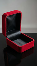 Red velvet jewelry box with black interior on a reflective surface