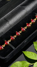 Gold bracelet with red gemstones on a black velvet background