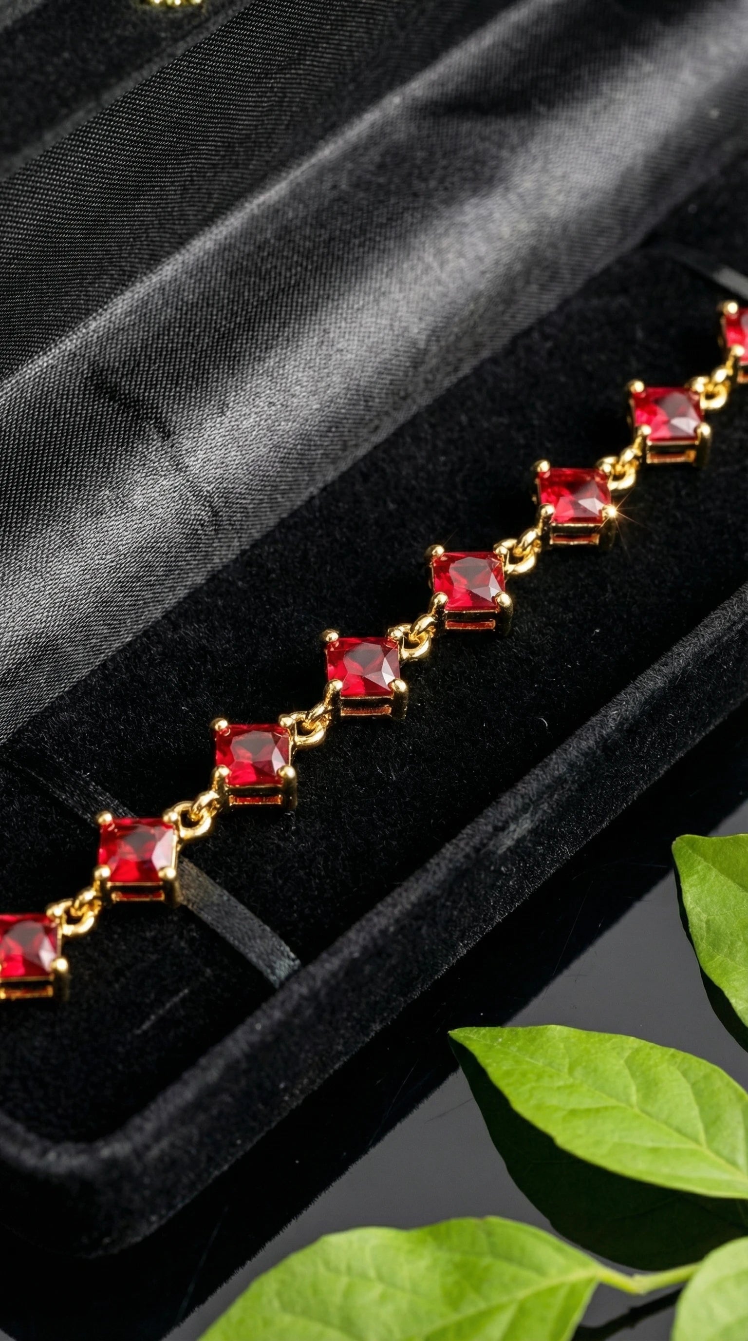 Gold bracelet featuring square red gemstones linked together, worn on a wrist.